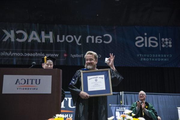 Dr. Adam Pack holds up the framed Crisafulli Award at the 2024 Commencement Ceremony.